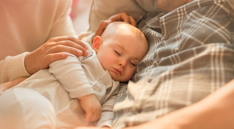 baby sleeping in dad arm