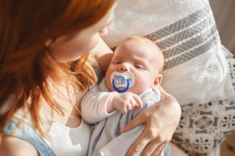 mom holding a baby with pacifier